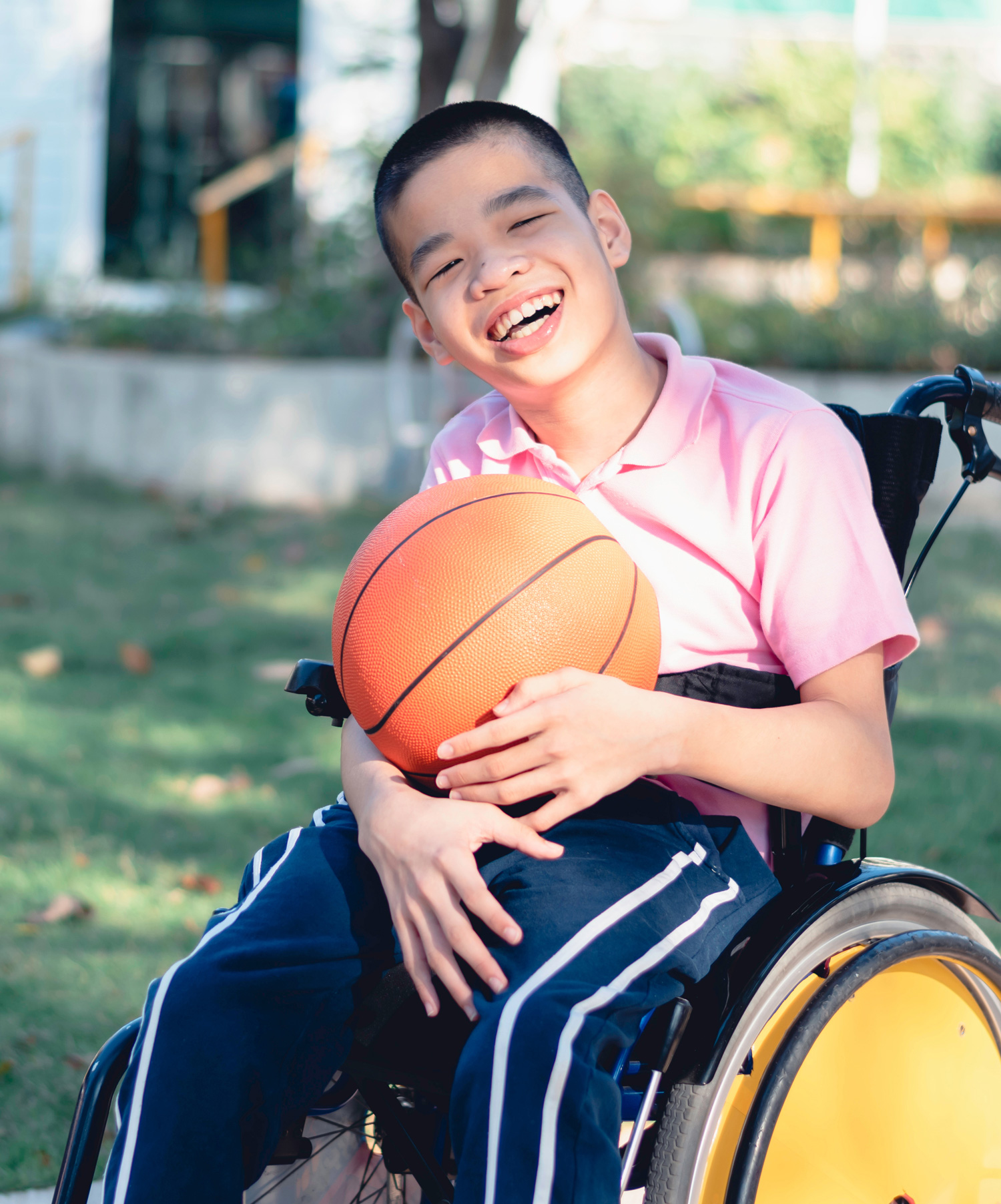 Summer Camp Inclusion Program - child outside in wheelchair with basketball